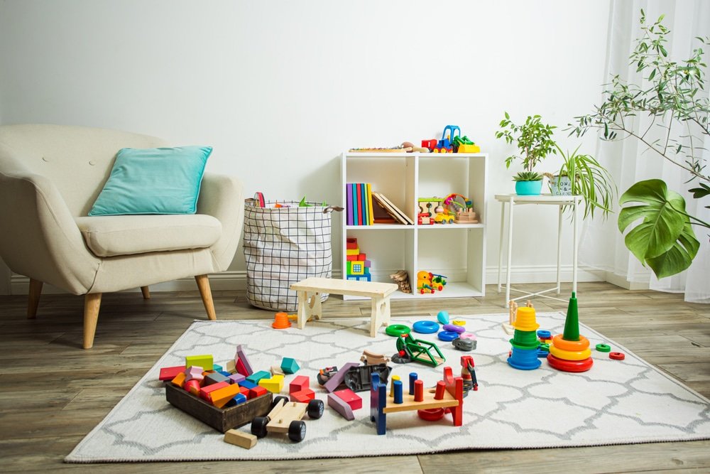 Lichte groepsruimte met speelvloer, lage tafels en kinderstoeltjes in een kinderdagverblijf