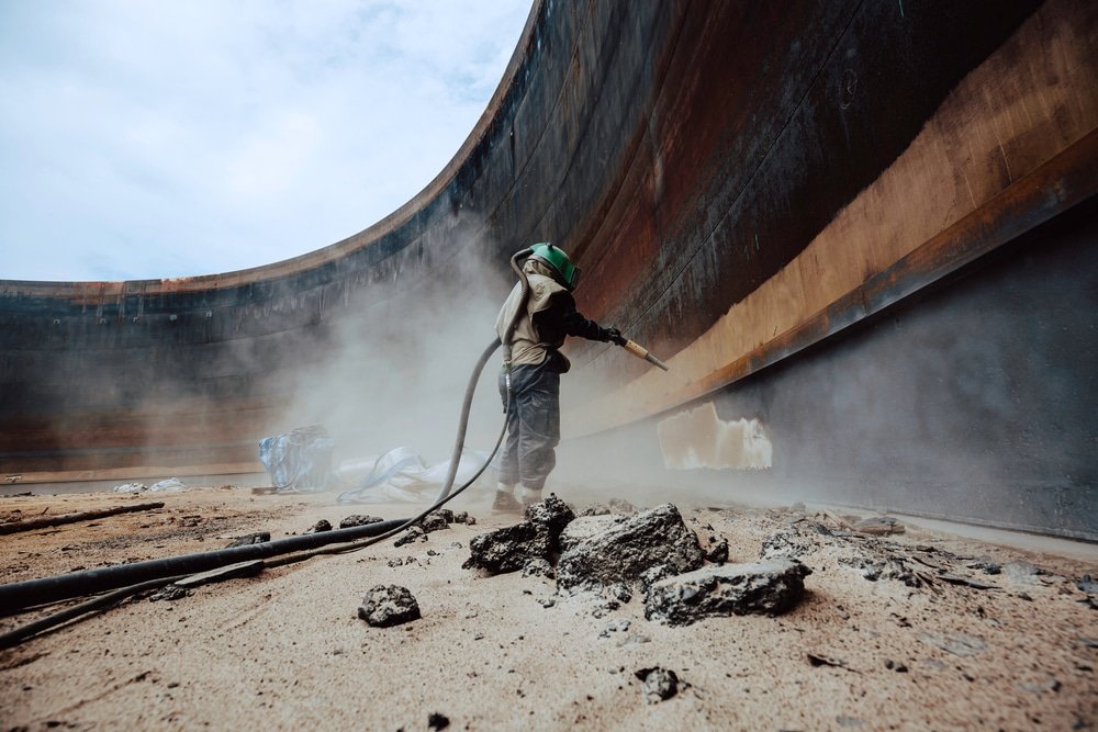 Zandstralen op industriële tank met oude lagen en vervuiling